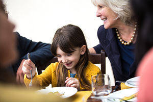 Girl eating happily at family meal with grandmother