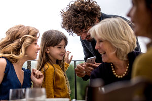 Generations of family all looking at smartphone together