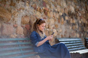 Young adult female using smartphone, sitting on a bench