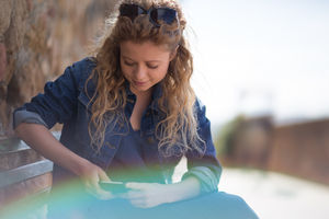 Young adult female using smartphone, sitting on a bench