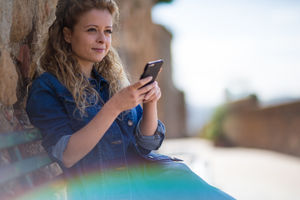 Young adult female using smartphone, sitting on a bench