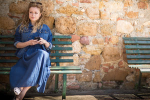 Young adult female using smartphone, sitting on a bench