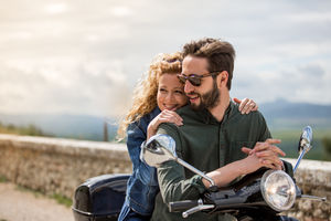 Young couple on motorbike together looking at view
