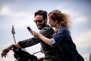 Young couple on motorbike together looking at smartphone