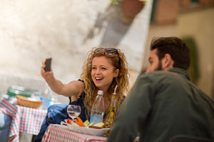 Young couple eating alfresco taking a selfie