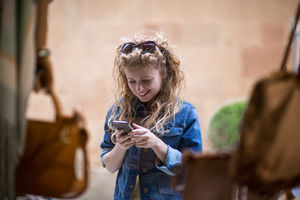 Young female window shopping and using smartphone