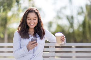 Woman sitting on bench checking smartphone