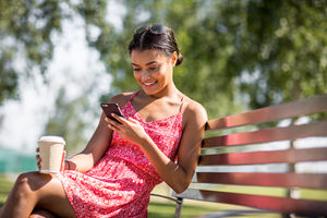 Woman sitting on bench checking smartphone