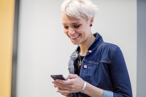 Young adult walking down street and checking smartphone