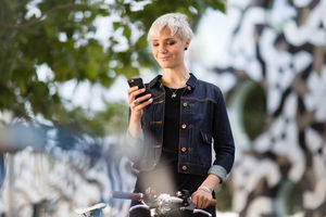 Young adult walking down street and checking smartphone