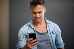 Young adult walking down street checking smartphone