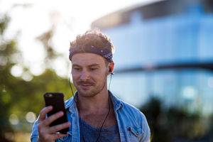 Young adult walking down street listening to smartphone