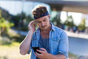 Young adult walking down street listening to smartphone