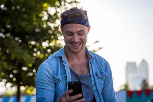 Young adult walking down street using smartphone