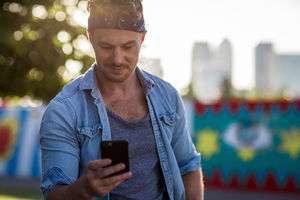 Young adult walking down street using smartphone