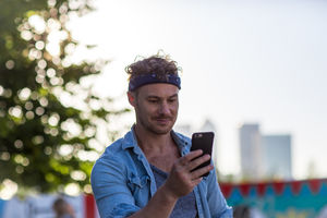 Young adult walking down street using smartphone