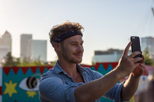 Young adult walking down street using smartphone camera