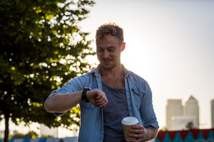 Young adult walking down street using smartwatch