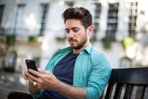 Tourist sitting on bench in London looking at smartphone