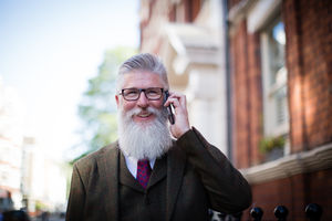 Senior male walking down street using smartphone