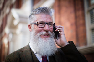 Senior male walking down street using smartphone