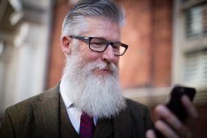 Senior male walking down street using smartphone