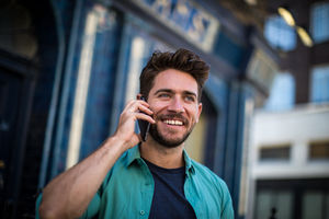 Young adult standing outside London pub using smartphone