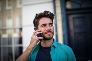 Young adult leaving his home on smartphone