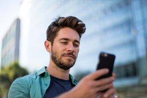 Young adult walking down street using smartphone