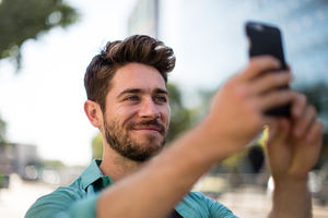 Young adult walking down street using smartphone
