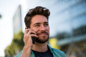 Young adult walking down street using smartphone