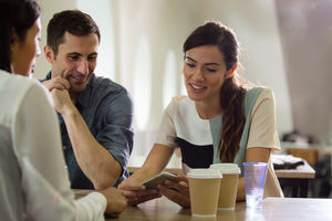 Colleagues in café looking at smartphone