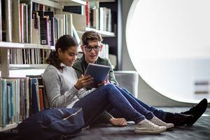 Students reading digital tablet in library