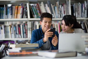 Students looking at smartphone in library
