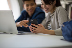 Students looking at smartphone in library