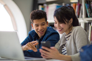 Students looking at smartphone in library
