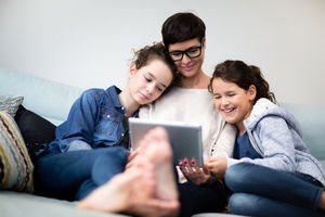 Mum and daughters watching show on digital tablet