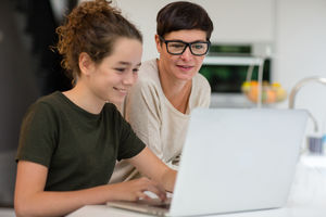 Daughter showing mum her homework on laptop