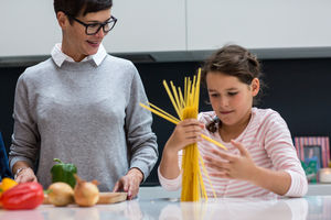 Daughter helping Mum cook spaghetti