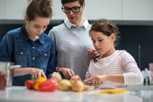 Mum teaching daughters to chop vegetables