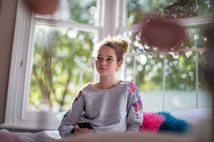 Teenager in bedroom holding smartphone