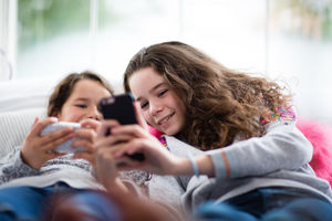 Sisters using smartphones in bedroom