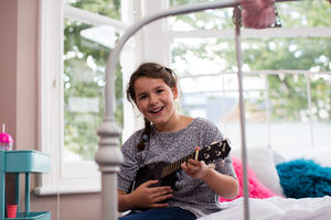 Girl playing a ukulele looking at camera