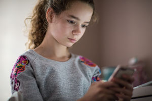 Teenager in bedroom looking at smartphone