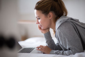 Young adult female using a laptop in bed