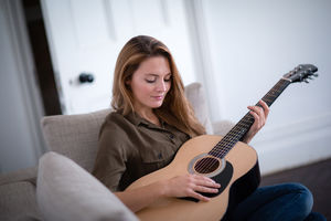 Young adult female playing acoustic guitar