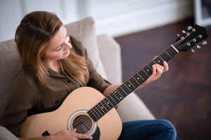 Young adult female playing acoustic guitar