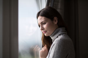 Young adult female looking out of window in winter