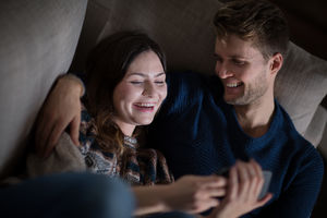 Couple looking at smartphone on sofa