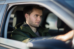 Young adult male driving car